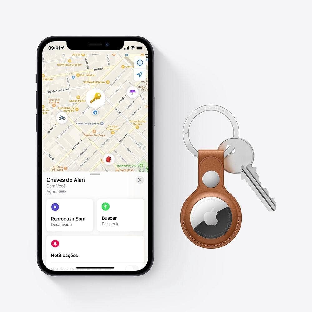 Imagem de um iPhone exibindo o mapa do aplicativo 'Buscar' com a localização das chaves do Alan, junto a um chaveiro de couro com um AirTag acoplado.