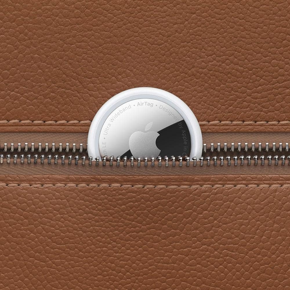 AirTag da Apple sobreposto a uma superfície de couro marrom, ao lado de um zíper, destacando seu design elegante e discreto.