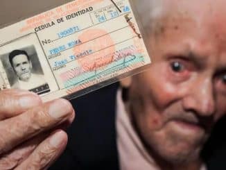 Juan Vicente Pérez, idoso, segura sua cédula de identidade venezuelana com uma foto de sua juventude.