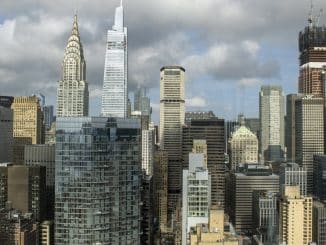 Vista da densa paisagem urbana de Manhattan com arranha-céus dominando o horizonte sob um céu parcialmente nublado.