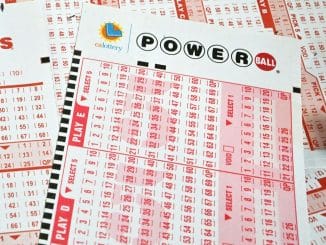 Pilha de bilhetes de loteria Powerball com números selecionados aguardando o próximo grande sorteio.