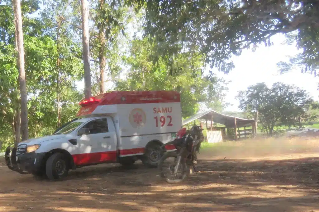 Ambulância do SAMU acelera em estrada rural em direção ao atendimento de emergência.