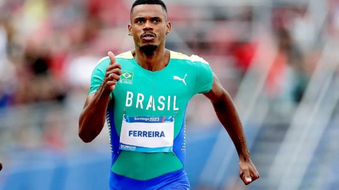 Atleta brasileiro Ferreira correndo durante uma competição de decatlo, vestindo uniforme verde e azul com a bandeira do Brasil e o nome "Ferreira" na etiqueta.