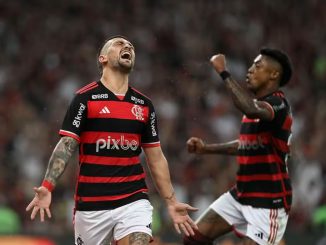 Jogador do Flamengo, Giorgian De Arrascaeta, comemora efusivamente após marcar o gol da vitória contra o Bahia, enquanto Bruno Henrique ergue o punho em celebração.