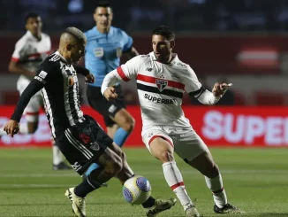 Jogadores de Atlético-MG e São Paulo em disputa acirrada pela bola durante partida válida pelas quartas de final da Copa do Brasil, com árbitro observando ao fundo.