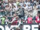 Jogador do Atlético-MG disputa bola aérea com jogador do Flamengo em partida intensa do Campeonato Brasileiro, com torcida ao fundo.