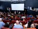 Evento com painel de discussão sobre mineração, audiência em um cinema.