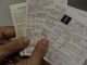 Close-up de uma mão segurando um smartphone que exibe um aplicativo de emissão de notas fiscais eletrônicas com gráficos e dados numéricos.