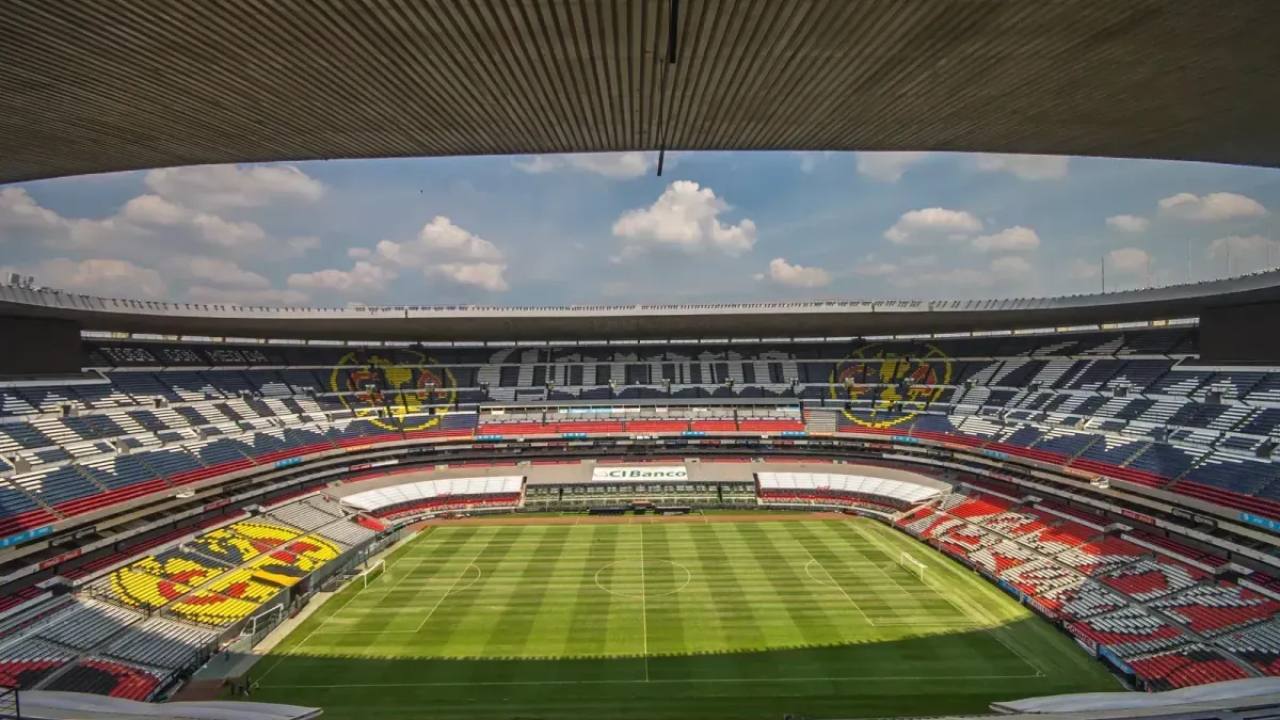Vista interna do Estádio Azteca, iluminado sob um céu azul feliz