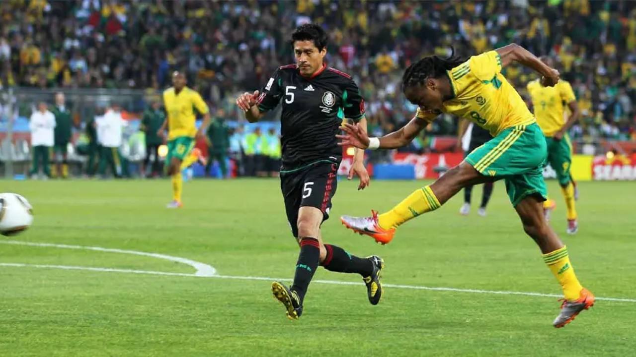 Jogadores de futebol do México e da África do Sul em ação durante o jogo.
